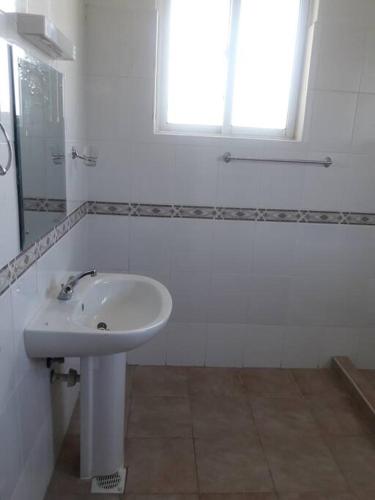 a white bathroom with a sink and a window at Blue Waters Villas in Ukunda