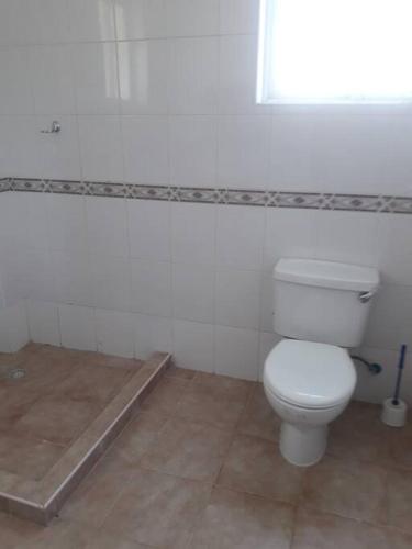 a white bathroom with a toilet and a window at Blue Waters Villas in Ukunda