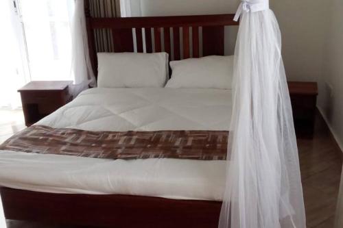 uma cama com uma cabeceira em madeira e um lençol branco em Blue Waters Villas em Ukunda