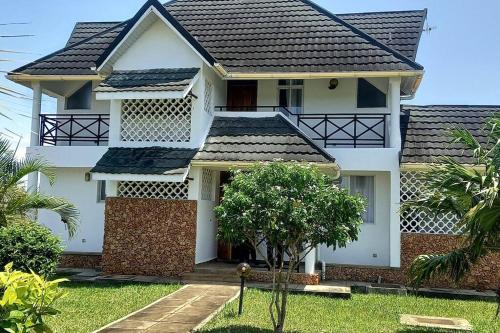 a white house with a black roof at Blue Waters Villas in Ukunda