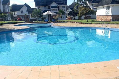 uma grande piscina com água azul numa casa em Blue Waters Villas em Ukunda