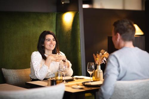 a man and a woman sitting at a table in a restaurant at Terre Blanche Hotel Spa Golf Resort in Tourrettes