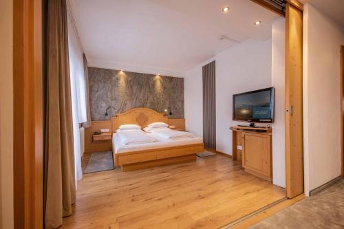 a bedroom with a bed and a flat screen tv at Familien- & Vitalhotel Auenhof in Fulpmes