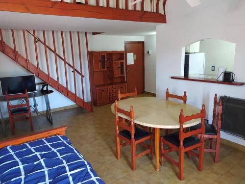 cocina y comedor con mesa y sillas en Departamentos Familiares Rosas Rojas en Villa Gesell
