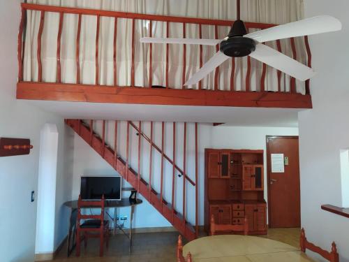 un ventilador de techo en una sala de estar con una escalera en Departamentos Familiares Roses Rojas en Villa Gesell