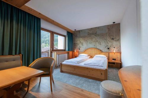 sypialnia z łóżkiem, stołem i krzesłami w obiekcie Familien- & Vitalhotel Auenhof w mieście Fulpmes
