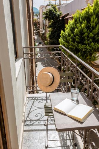 a table with a hat and a book on a balcony at Neratze Hammam Suites in Rethymno Town