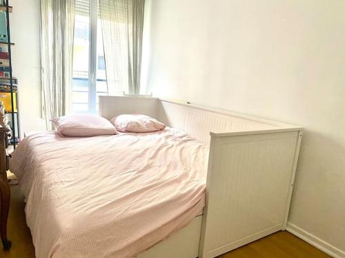 ein Bett mit zwei Kissen in einem Zimmer mit einem Fenster in der Unterkunft Grand appartement cosy avec balcon 6 personnes in Saint-Ouen