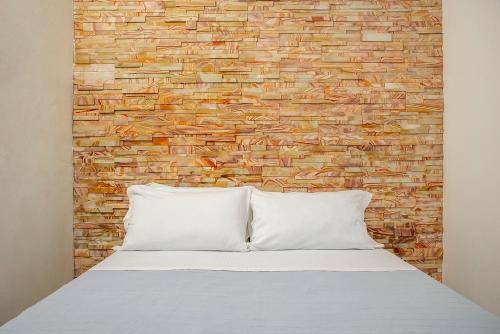 a bed with two pillows in front of a brick wall at Appartamento a Ortigia in Syracuse
