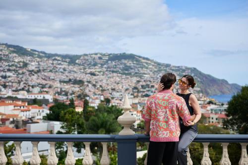 a man and woman standing on a balcony looking at a city at Luna Rossa by Homie in Funchal