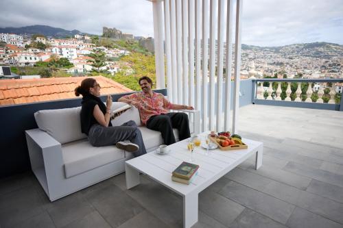 a man and woman sitting on a couch on a balcony at Luna Rossa by Homie in Funchal