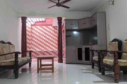 a living room with chairs and a ceiling fan at Cheerful home in Mysore