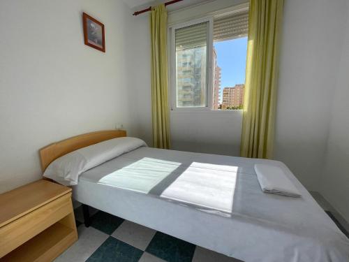 1 dormitorio con cama y ventana en Apartamentos Bonaire 3000, en Oropesa del Mar