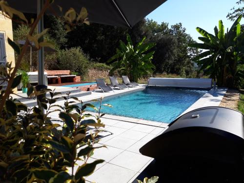 une piscine avec des chaises longues et un parasol dans l'établissement Le Logis, à Vitrac