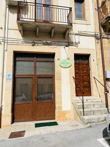 a building with two wooden doors and a balcony at Holiday Home Castle Salemi - Casa Vacanze in Salemi