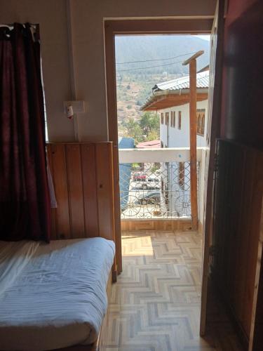 a bedroom with a bed and a view of a balcony at Tashi Yarphel in Pajo