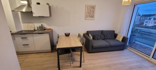 a living room with a table and a couch and a kitchen at Une jolie vue - Appt 2 pièces Vue mer Balcon sud in Wimereux