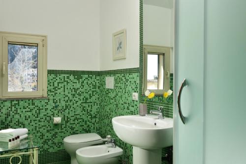 a green bathroom with a sink and a toilet at Hotel Recostano Residence in Trevignano Romano