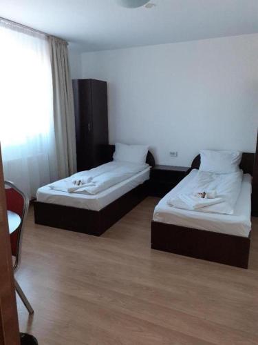 a hotel room with two beds and a window at Pensiunea Otopeni in Otopeni