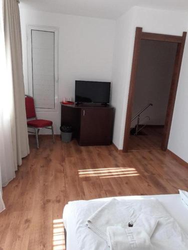 a room with a bed and a television and a chair at Pensiunea Otopeni in Otopeni