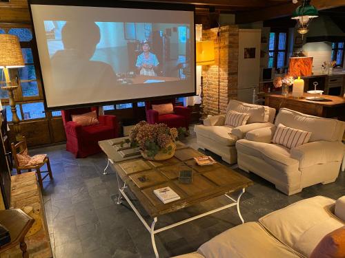 a large screen in a living room with a tv at LA QUINTA DE PUELLES in Ambás