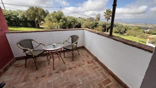 a patio with two chairs and a table on a balcony at Hotel Sindhura in Vejer de la Frontera