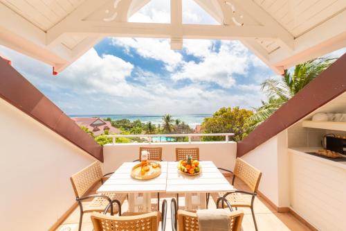 balcone con tavolo, sedie e vista sull'oceano di Résidence Pierre & Vacances Premium Les Tamarins a Sainte-Anne
