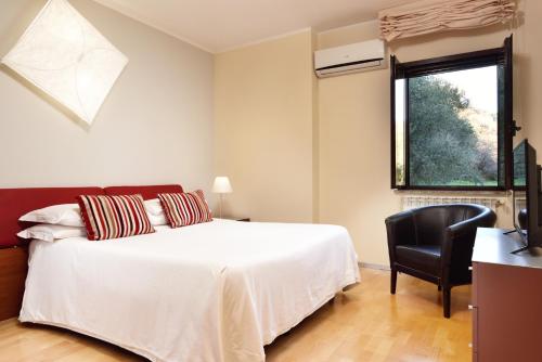 a bedroom with a bed and a chair and a window at Hotel Recostano Residence in Trevignano Romano
