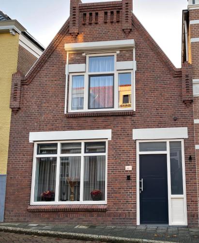 a brick house with white windows and a door at Bed & Wellness Chinel Luxe vakantiehuis met Sauna's en Bubbelbad in Sint Annaland