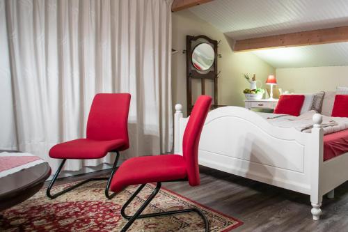 een slaapkamer met een bed en twee rode stoelen bij de Huttert Opkamer in Luttenberg