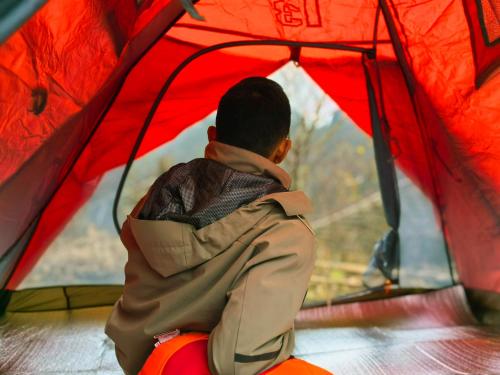 a man sitting in a tent looking out the window at Zhangjiajie National Forest Park Camping in Zhangjiajie