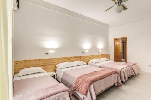 three beds in a room with a ceiling fan at Hotel Altavilla 9 in Rome
