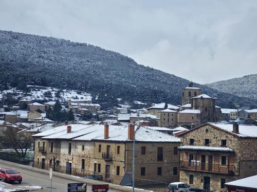 a town with snow covered buildings and a mountain at Hotel Virginia R.H. in Vinuesa