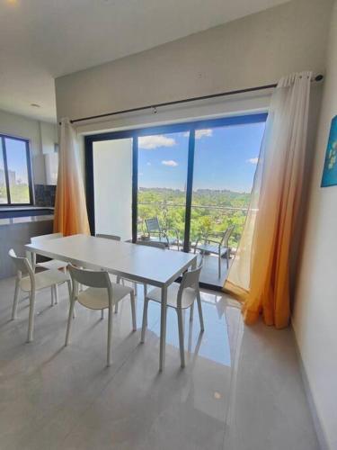 a table and chairs in a room with a large window at Happy Home 3BHK Condo - Muttukadu ECR in Chennai