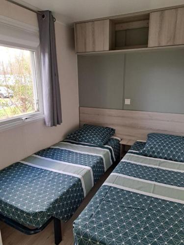 - 3 lits dans une chambre avec fenêtre dans l'établissement mobil home 3 chambres 2 sdb 750, à Pont-Aven