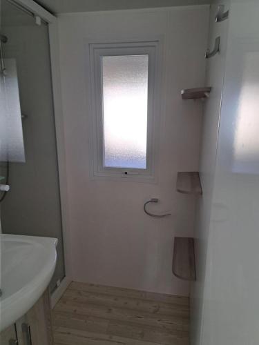 une salle de bain avec un lavabo et une fenêtre dans l'établissement mobil home 3 chambres 2 sdb 750, à Pont-Aven