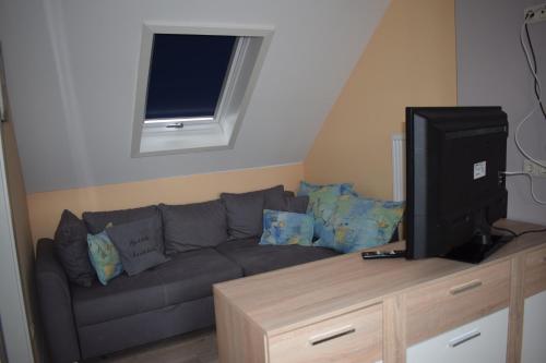 a living room with a gray couch and a television at Marktstübchen an der schönen Loreley in Bornich