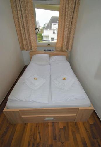 a small bed in a small room with a window at Strandperle - 100m zum Strand in Scharbeutz