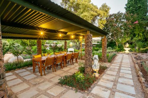 a patio with a table and chairs under a pergola at Die Fonteine Country Guesthouse and Glamping in Oudtshoorn