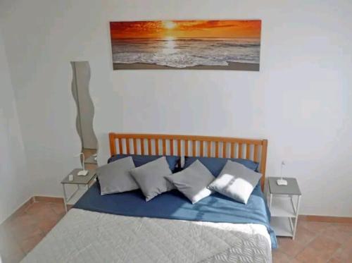 ein Schlafzimmer mit einem Bett mit Kissen und einem Gemälde an der Wand in der Unterkunft Casa Soprani - Relax Marchigiano in Castelfidardo