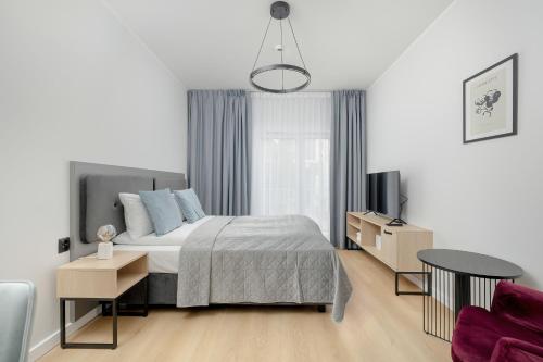 a white bedroom with a bed and a tv at Modern Studios in the Centre of Poznań by Noclegi Renters in Poznań