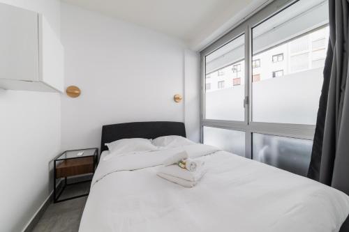une chambre avec un lit blanc avec une fenêtre dans l'établissement Charmant appartement calme place du Trocadéro - 4P - FLAT-GUEST, à Paris