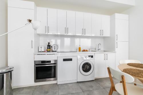 une cuisine avec des armoires blanches et une laveuse et une sécheuse dans l'établissement Charmant appartement calme place du Trocadéro - 4P - FLAT-GUEST, à Paris