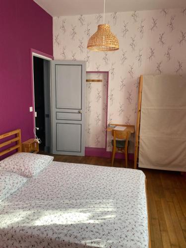 - une chambre avec un lit et un mur violet dans l'établissement Corbeilles, à Auxy