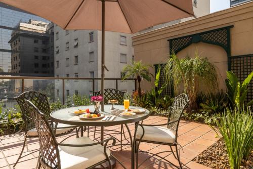 a table and chairs on a patio with an umbrella at L'Hotel PortoBay São Paulo in São Paulo