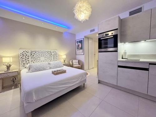 Cet appartement comprend une chambre avec un lit blanc et une cuisine. dans l'établissement Magnifique studio bohème neuf cœur de ville, à Antibes