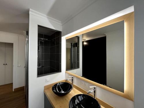 een badkamer met 2 zwarte wastafels en een grote spiegel bij Familial Apartment - Troyes in Troyes