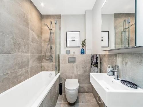 a bathroom with a sink and a toilet and a tub at Pass the Keys Modern 2-BR Penthouse Oasis Ideal for Business Family and Group Retreats in Trendy Fulham in London