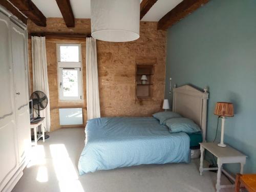 a bedroom with a blue bed and a brick wall at Maison en pierre avec piscine in Lavergne