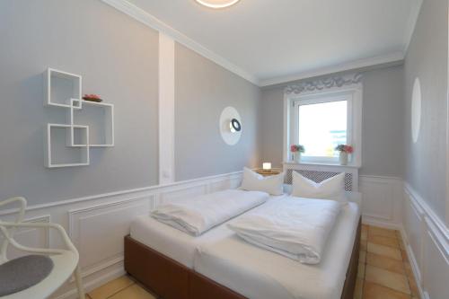 ヴェスターラントにあるPelzer Haus Atlantikのベッドルーム1室(白いシーツ付きのベッド1台、窓付)